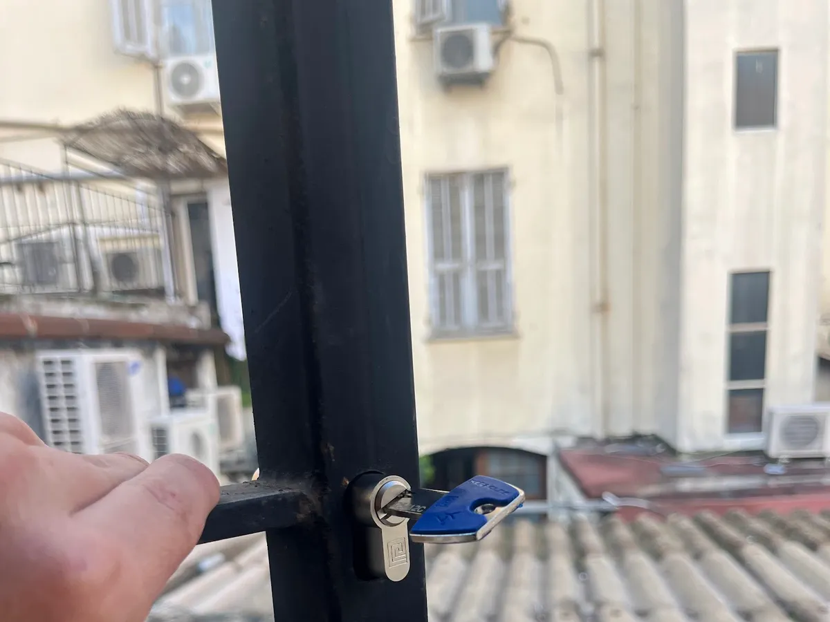 Clé dans une serrure de portail, vue sur les toits de Nice